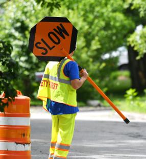Road worker holding a sign that reads "Slow"