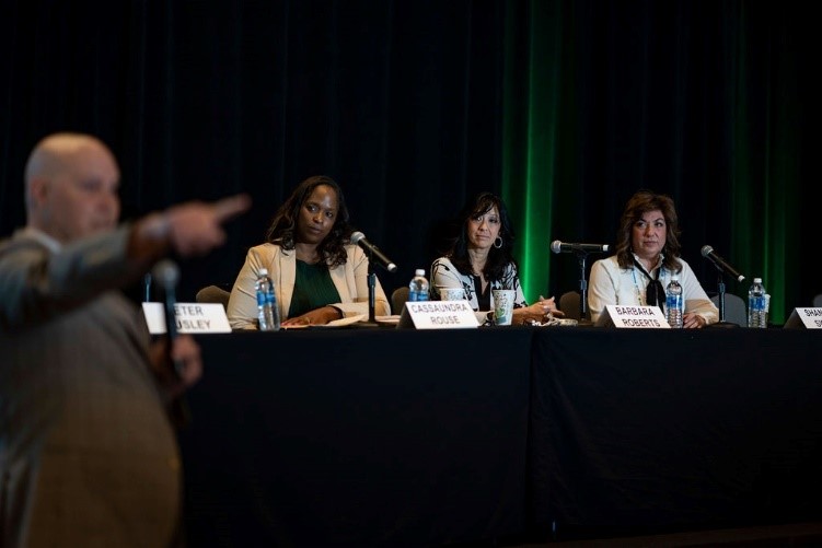 Photo of Peter ously moderating a panel with speakers at a table