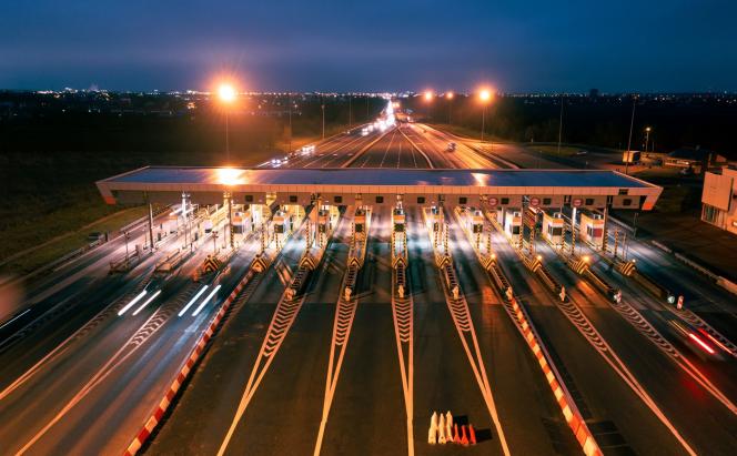 aerial view of a large toll gantry at night with streaming lights.