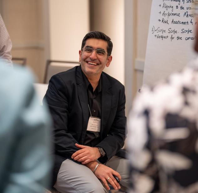 Person smiling sitting in chair near a White Board