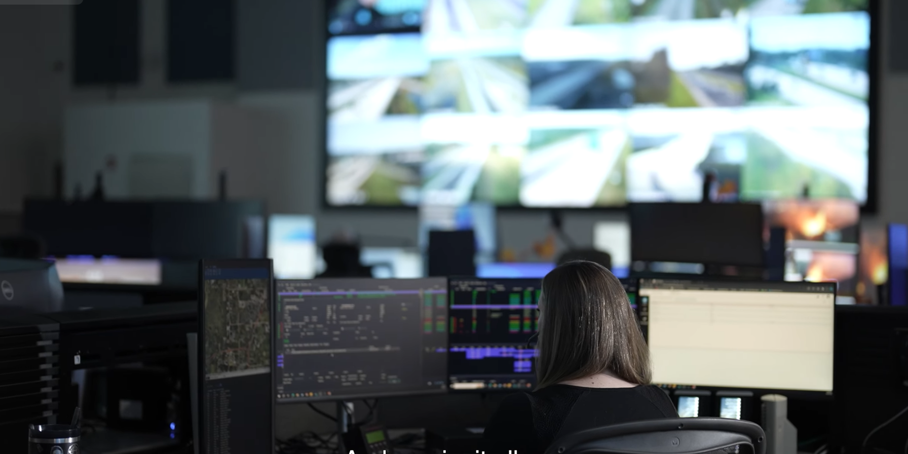 person in customer service center viewing multiple large screens