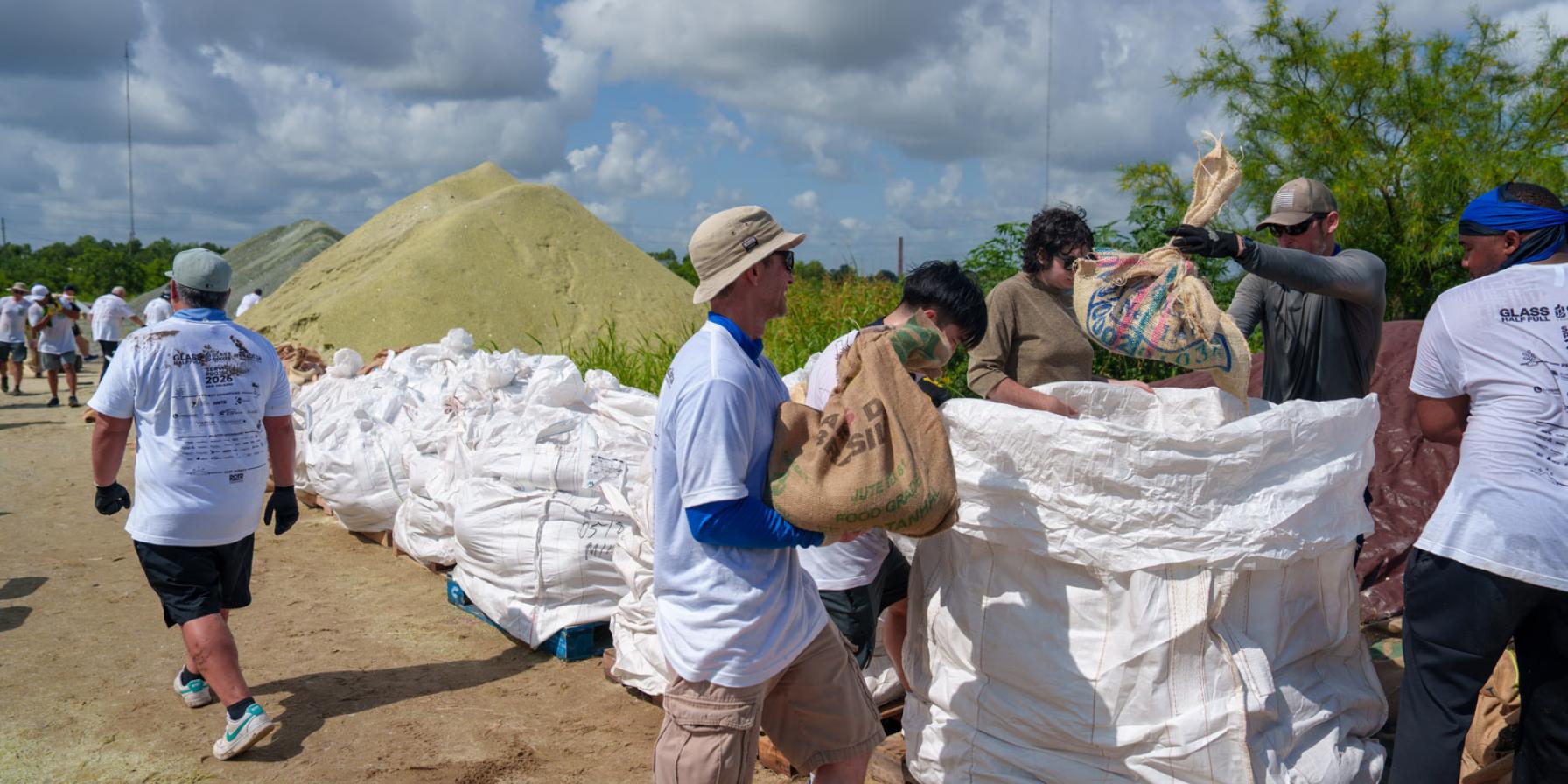 People carrying and filling bags of glass sand