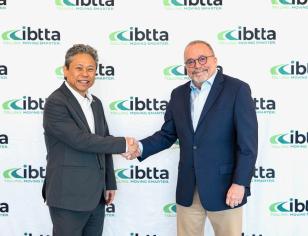 two men handshaking in front of an IBTTA Step & Repeat showing IBTTA's logo