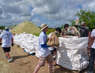 People carrying and filling bags of glass sand