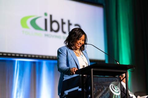 Joi Taylor Dean standing at podium with IBTTA banner in the background