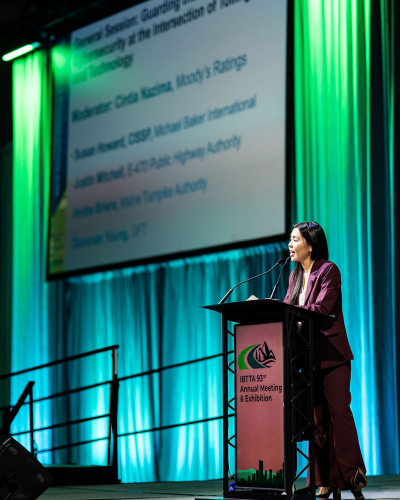 Person standing at a podium with a screen in background