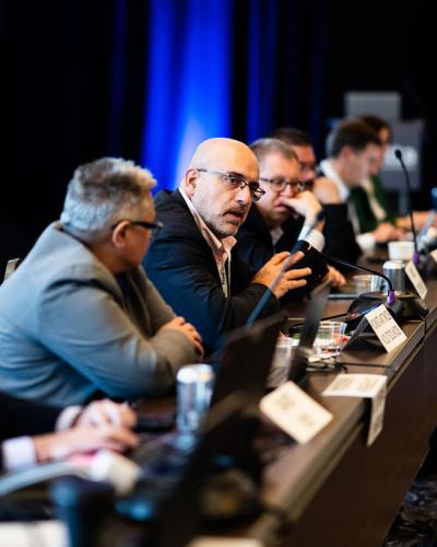 Blurred people sitting at a table with one man in focus who is talking